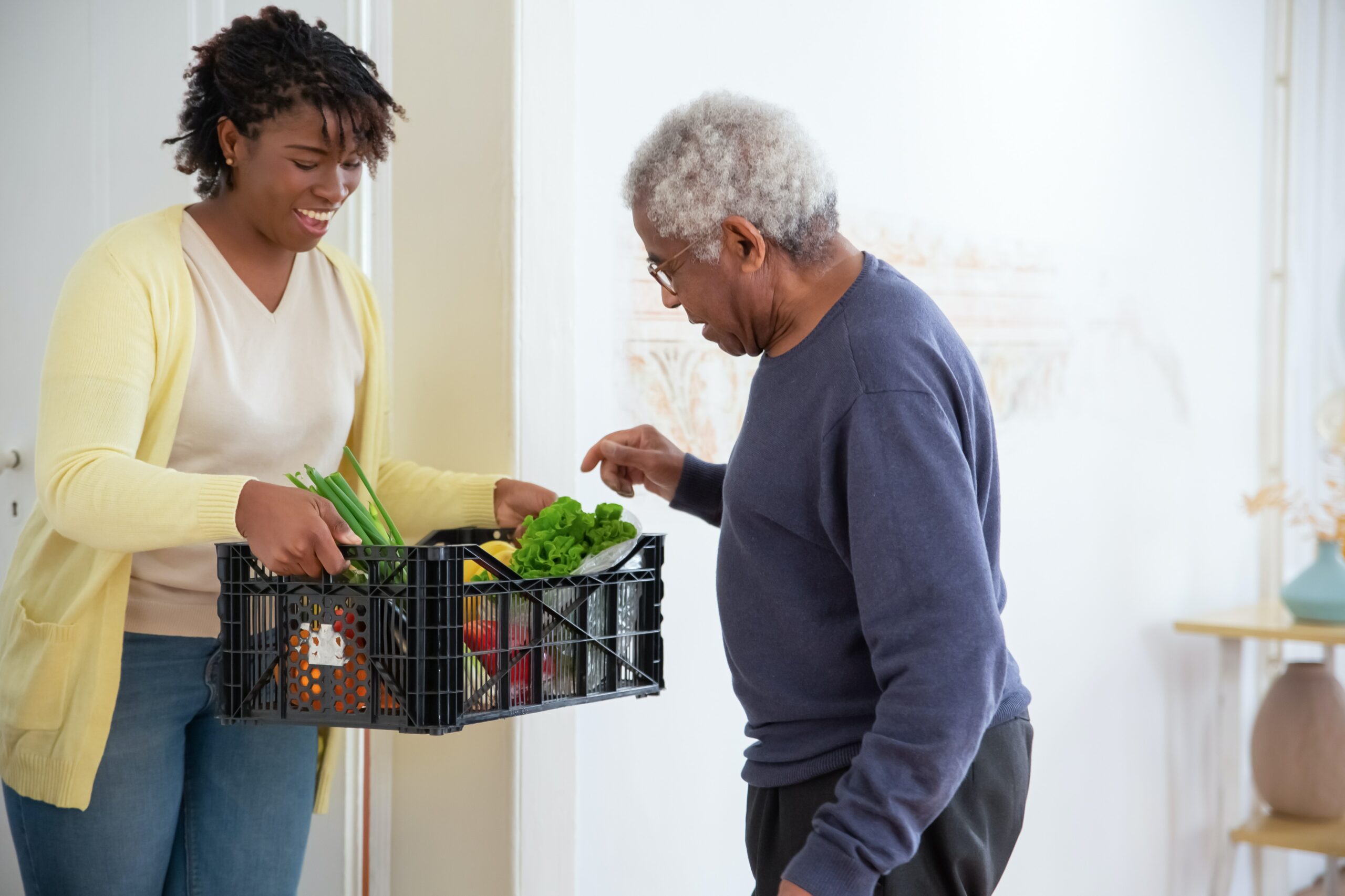 photo of woman helping elderly man with groceries